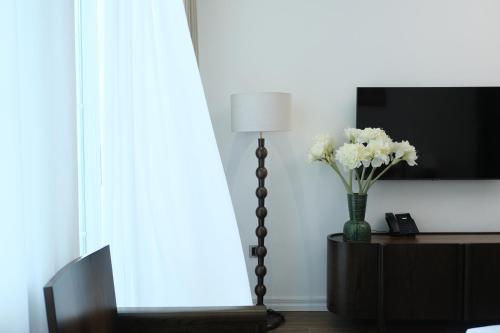 a vase of flowers on a table with a lamp at Paul Chabot Hotel in Hai Phong