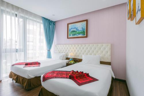 a hotel room with two beds and a window at New Century Hotel in Hanoi
