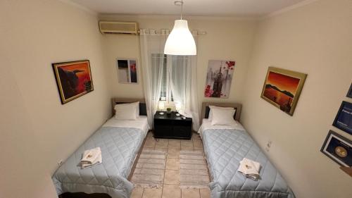 two beds in a room with paintings on the walls at Patras Centre Apartment in Patra
