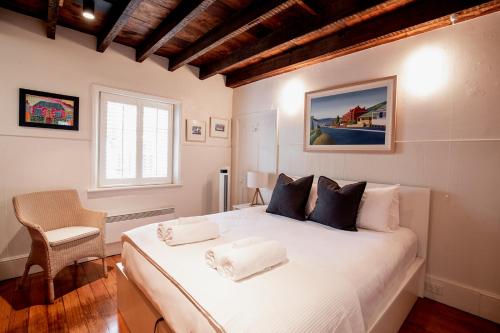 una camera con un letto bianco, una sedia e una finestra di Inner-city sanctuary with off-street parking a Hobart