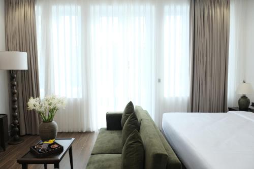 a hotel room with a bed and a couch at Paul Chabot Hotel in Hai Phong