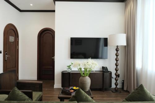 a living room with a couch and a tv at Paul Chabot Hotel in Hai Phong