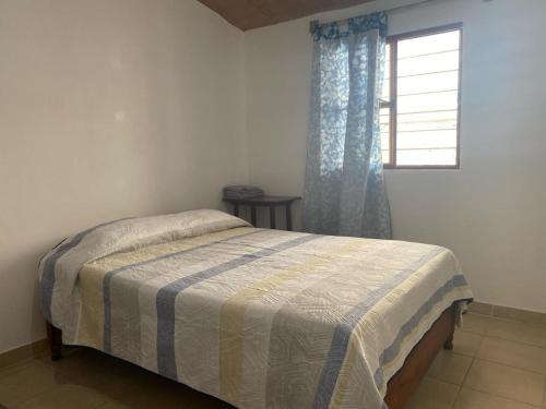 a bed in a bedroom with a window and a bedspread at Kochian: Lugar donde se sueña in Zoquiapan