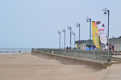 a sandy beach with a pier with flags and lights at Cozzzy Seaside Retreat in Mablethorpe