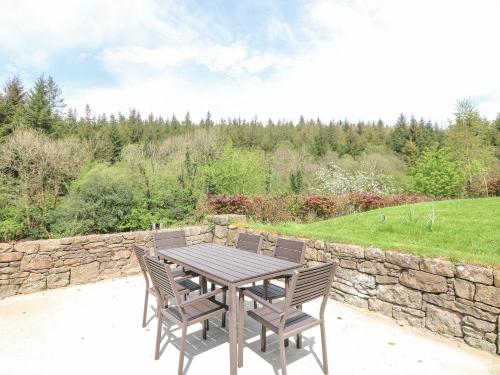 a wooden table and chairs on a patio with a stone wall at Coffeys in Ballymacarbry