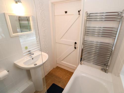 a bathroom with a sink and a glass shower door at Tregonning Lodge in Helston