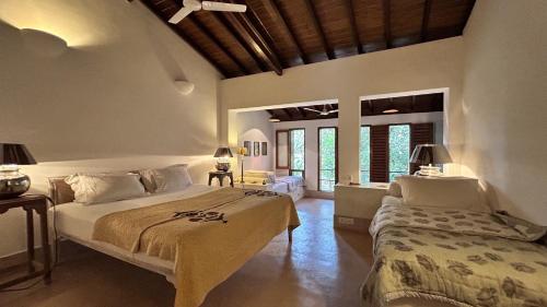 a bedroom with two beds in a room with windows at SaffronStays Stella Maris - Luxury Beach Front Villa Near Redi Beach in Querim
