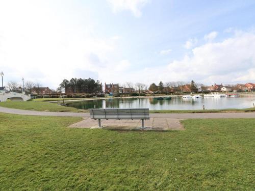 a park bench sitting next to a body of water at Cozzzy Seaside Retreat in Mablethorpe
