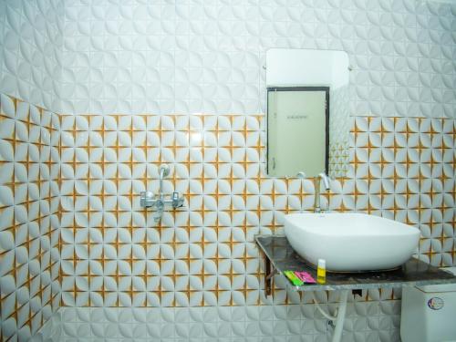 ein Bad mit einem Waschbecken und einem Spiegel in der Unterkunft Hotel Blossom in Lucknow