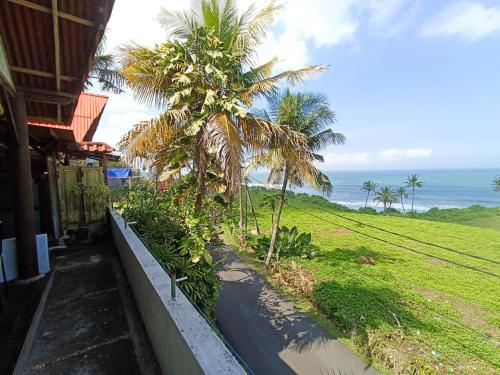 a view of the ocean from a house with a palm tree at Pondok Pisces Bungalows Balian Beach in Selemadeg