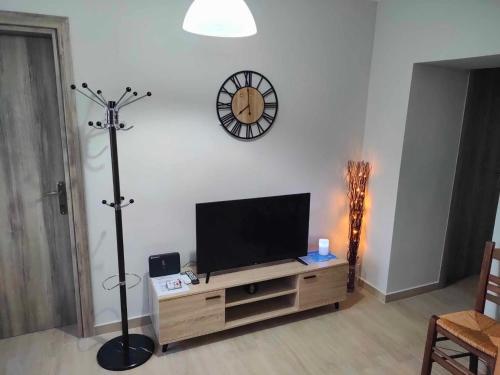 a living room with a television and a clock on the wall at PANOS HOUSE in Makri