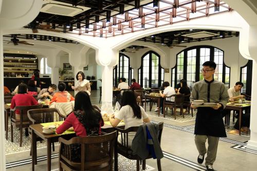 a group of people sitting at tables in a restaurant at Paul Chabot Hotel in Hai Phong