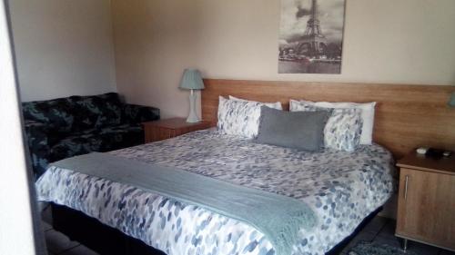 a bedroom with a bed and a couch at 12 On Vaal Drive Guesthouse in Vanderbijlpark