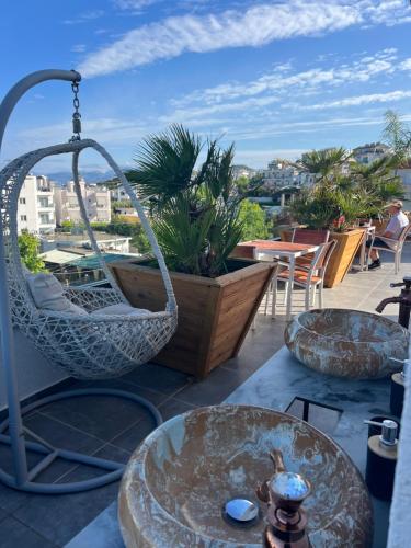 a patio with a swing chair and tables on a roof at Ilio Boutique Hotel in Ksamil
