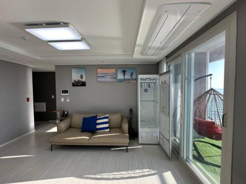 a living room with a couch and a window at The Gangneung Ocean Stay in Gangneung