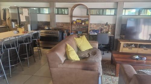 a living room with a couch and a kitchen at 12 On Vaal Drive Guesthouse in Vanderbijlpark