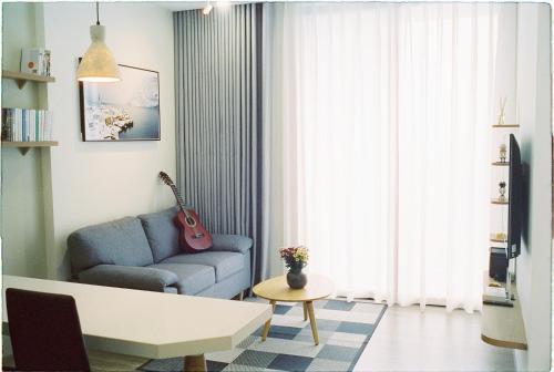 sala de estar con sofá azul y guitarra en Tofu's House - 2 BR APT in Sol Forest - Ecopark, en HÆ°ng YÃªn