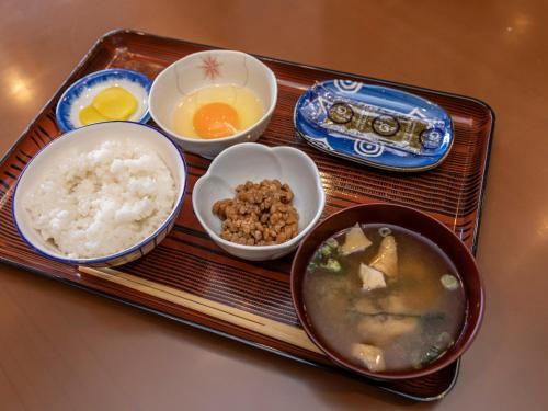 a tray with rice and bowls of food on it at Asahi sauna Capsule Inn Hirosaki in Hirosaki