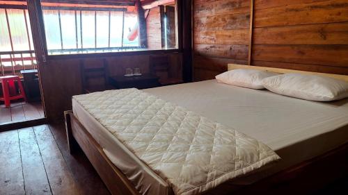 un grande letto in una camera con pareti in legno di nhà gỗ homestay nguyên văn a Hưng Lương