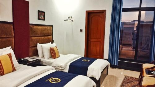 a hotel room with two beds and a window at Hotel Swat Rezidor by Khan Familia Travels in Swat