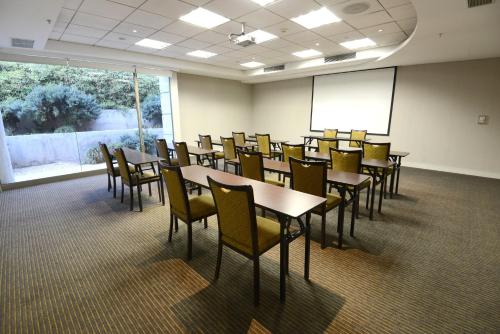 a conference room with tables and chairs and a screen at Holiday Inn Santiago - Airport Terminal by IHG in Santiago