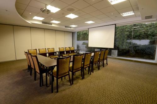 a conference room with a table and chairs and a screen at Holiday Inn Santiago - Airport Terminal by IHG in Santiago
