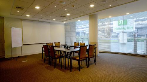 a conference room with a table and chairs and a whiteboard at Holiday Inn Santiago - Airport Terminal by IHG in Santiago