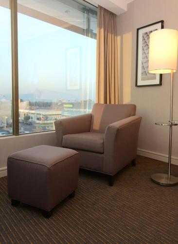 a living room with a chair and a ottoman and a window at Holiday Inn Santiago - Airport Terminal by IHG in Santiago