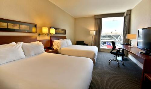 a hotel room with two beds and a television at Holiday Inn Santiago - Airport Terminal by IHG in Santiago