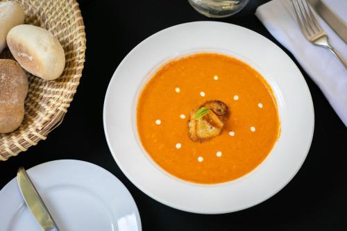 a white plate with a bowl of soup on a table at Holiday Inn Santiago - Airport Terminal by IHG in Santiago
