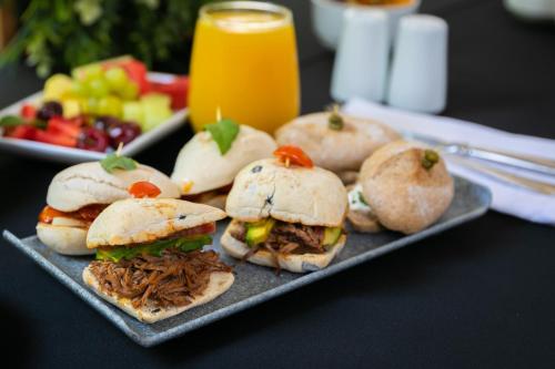 a plate of pulled pork sandwiches and a plate of fruit at Holiday Inn Santiago - Airport Terminal by IHG in Santiago