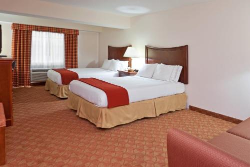 a hotel room with two beds and a couch at Holiday Inn Express Murrysville - Delmont, an IHG Hotel in Delmont