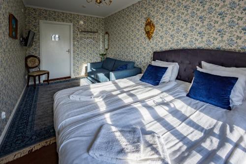 a bedroom with a large bed with blue pillows at Mjällbyhus Pensionat & Stugby in Sölvesborg