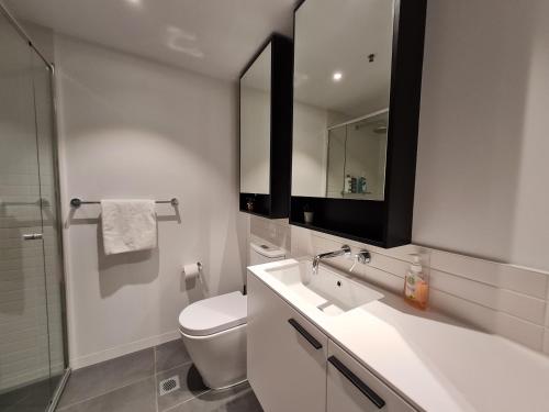 uma casa de banho com um WC, um lavatório e um espelho. em Serenity 1br Flemington Balcony Pool Free Park em Melbourne