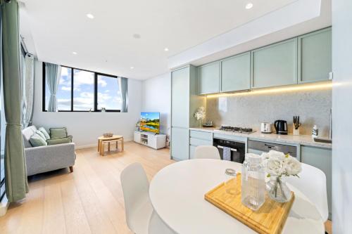 a kitchen and living room with a white table and chairs at High level urban retreat in Macquarie Park in Sydney