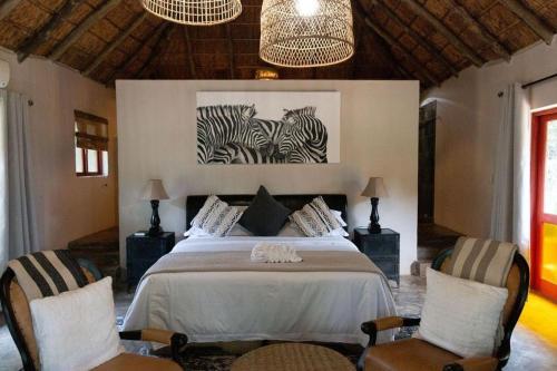 a bedroom with a bed with two zebras on the wall at Mologa River Lodge in Rust de Winter