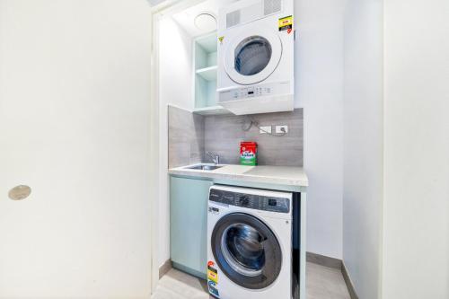 a laundry room with a washing machine and a washer and dryer at High level urban retreat in Macquarie Park in Sydney