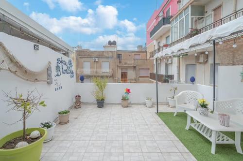 an outdoor patio with white furniture and potted plants at SFEA HOME in Pachino