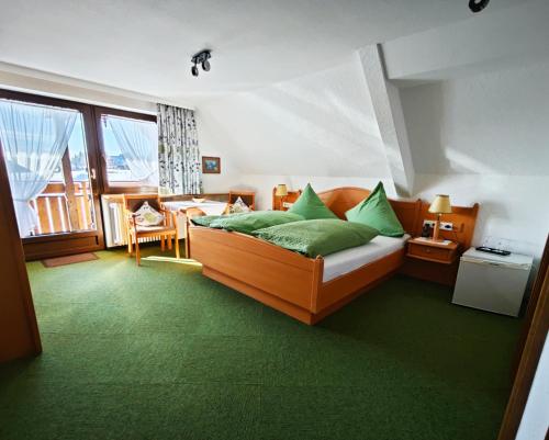 sypialnia z łóżkiem z zielonymi poduszkami w obiekcie Café-Pension Feldbergblick w mieście Titisee-Neustadt