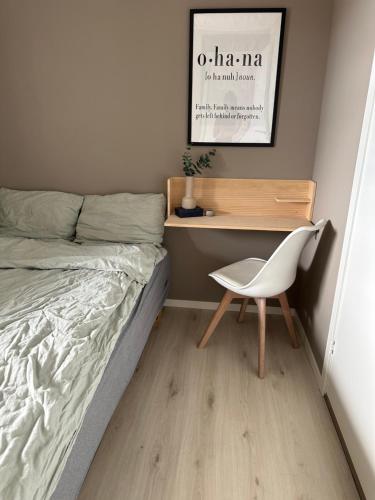 a bedroom with a bed and a desk and a chair at Koselig leilighet nær bussholdeplass og natur. in Tromsø