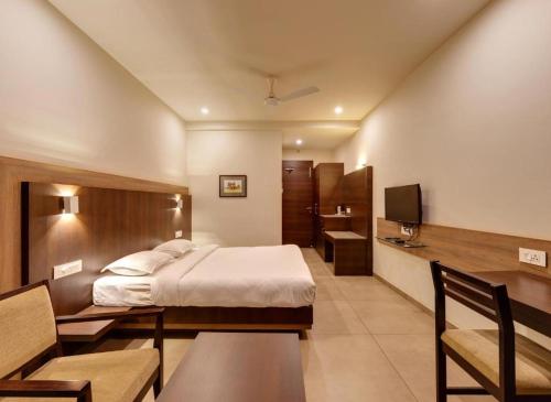 a bedroom with a bed and a desk and a television at Hotel Classic Mid Town, Kolhapur NEAR MAHALAXMI TEMPLE in Kolhapur