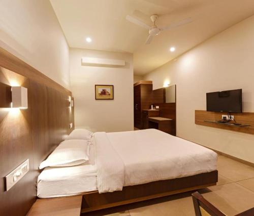 a bedroom with a white bed and a television at Hotel Classic Mid Town, Kolhapur NEAR MAHALAXMI TEMPLE in Kolhapur