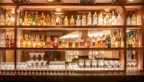 a bar filled with lots of bottles and glasses at Novotel Kolkata Hotel and Residences in Kolkata