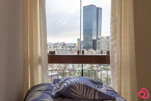 - un lit en face d'une fenêtre avec vue sur la ville dans l'établissement Departamento con vista al sunset, à Lima