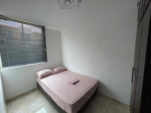 ein kleines Schlafzimmer mit einem Bett mit rosa Bettwäsche und einem Fenster in der Unterkunft Bello apartamento de 3 habitaciones in Cúcuta