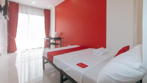 two beds in a room with a red wall at RedDoorz @ Aerial Hotel Los Baños in Los Baños