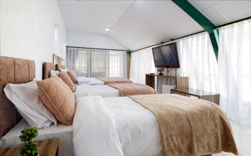 a bedroom with two beds and a television in it at Hotel Green Center Gili in Gostivar