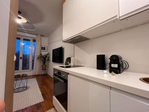 une cuisine avec des armoires blanches et un comptoir dans l'établissement Cosy - Magnifique vue sur parc Georges Brassens, à Paris