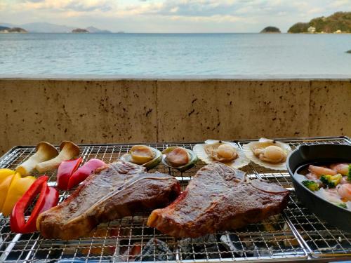 a grill with meat and vegetables and a bowl of food at Jakomaru Park Tsuda in Sanuki