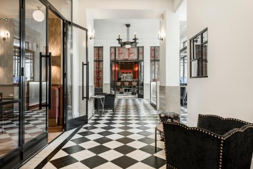 a hallway with a black and white checkered floor at Hôtel de la Poste in Beaune